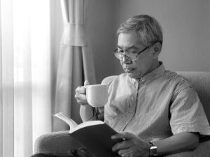 コーヒーを飲みながら読書をするシニア男性