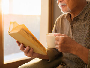 コーヒーを飲みながら読書をするシニア男性