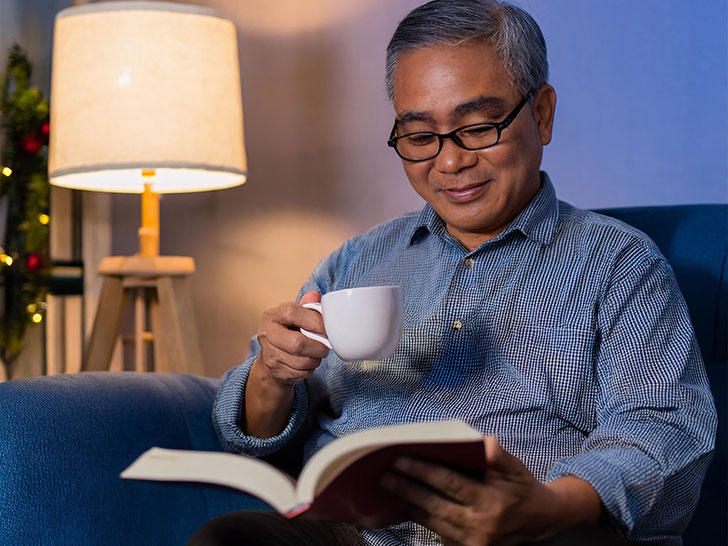 コーヒーを飲みながら読書をするシニア男性