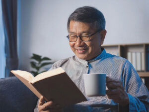 コーヒーを飲みながら読書をするシニア男性