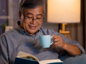 コーヒーを飲みながら読書をするシニア男性