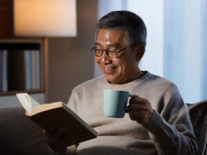 コーヒーを飲みながら読書をするシニア男性