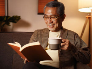 コーヒーを飲みながら読書をするシニア男性