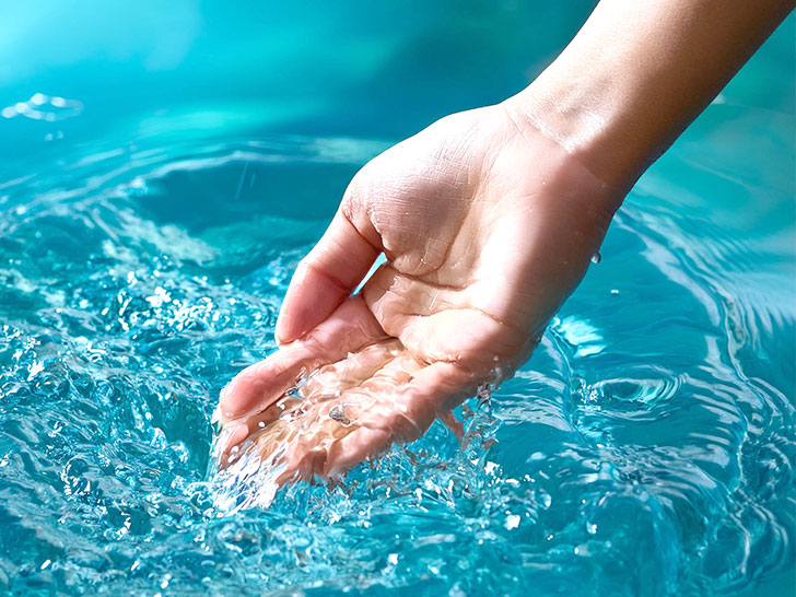 透明な水をすくう女性の手