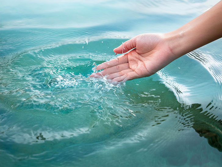 透明な水をすくう女性の手