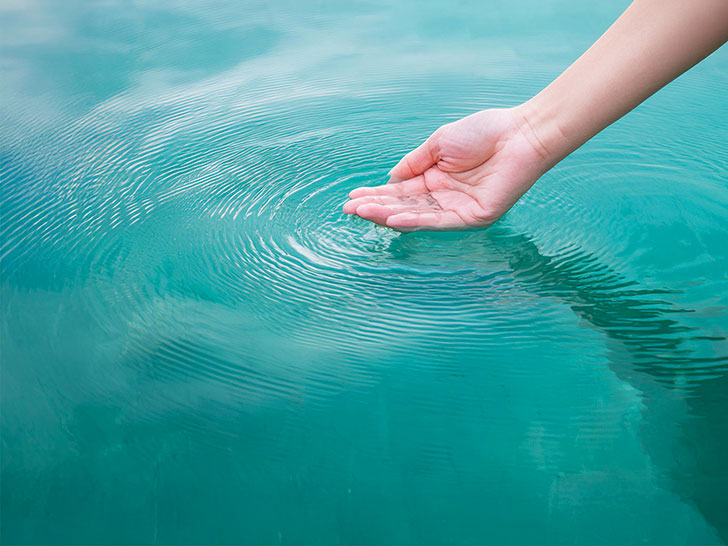 透明な水をすくう女性の手