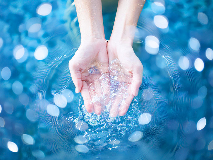 透明な水をすくう女性の手