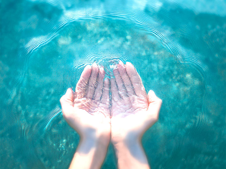 透明な水をすくう女性の手