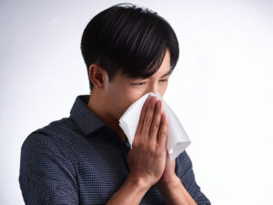 ティッシュで鼻をかむ若い男性