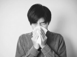 ティッシュで鼻をかむ若い男性