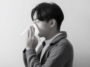 ティッシュで鼻をかむ若い男性