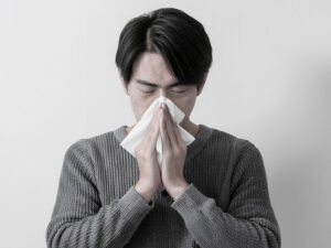 ティッシュで鼻をかむ若い男性