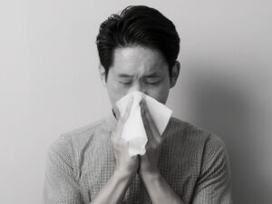 ティッシュで鼻をかむ若い男性