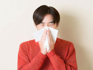 ティッシュで鼻をかむ若い男性