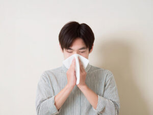 ティッシュで鼻をかむ若い男性