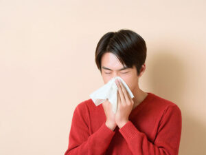 ティッシュで鼻をかむ若い男性