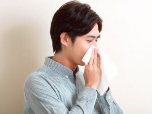 ティッシュで鼻をかむ若い男性