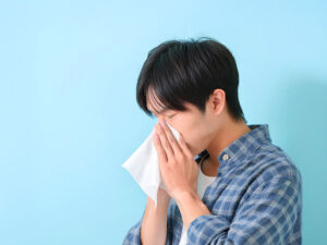 ティッシュで鼻をかむ若い男性