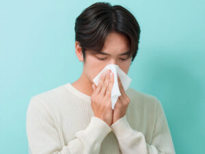 ティッシュで鼻をかむ若い男性