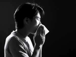 ティッシュで鼻をかむ若い男性