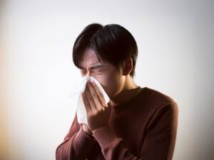 ティッシュで鼻をかむ若い男性