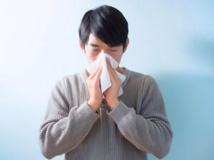 ティッシュで鼻をかむ若い男性