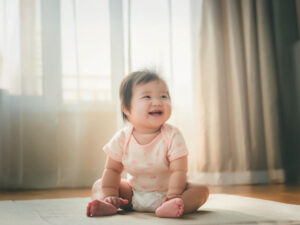 座ってとびきりの笑顔を見せる赤ちゃん