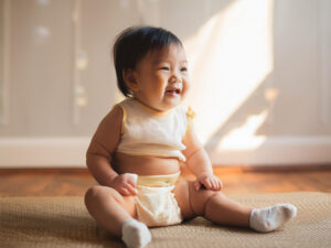 座ってとびきりの笑顔を見せる赤ちゃん