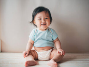 座ってとびきりの笑顔を見せる赤ちゃん