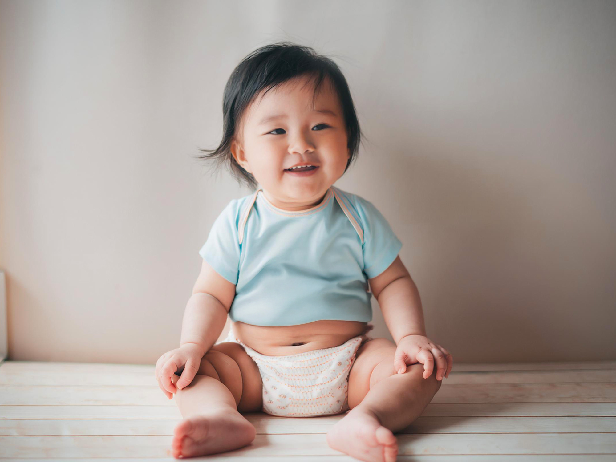 座ってとびきりの笑顔を見せる赤ちゃん