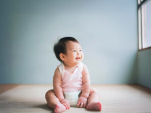 座ってとびきりの笑顔を見せる赤ちゃん