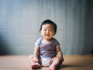 座ってとびきりの笑顔を見せる赤ちゃん