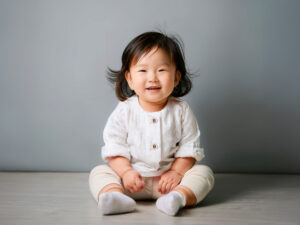 座ってとびきりの笑顔を見せる赤ちゃん