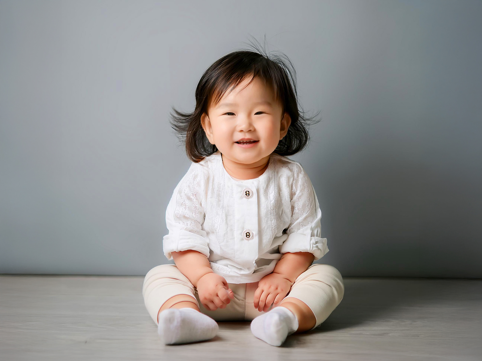 座ってとびきりの笑顔を見せる赤ちゃん