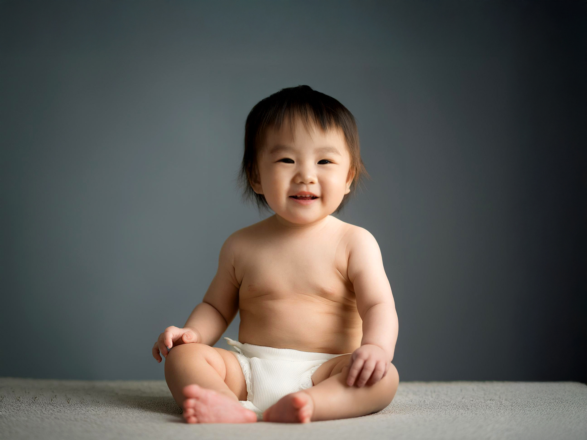 座ってとびきりの笑顔を見せる赤ちゃん