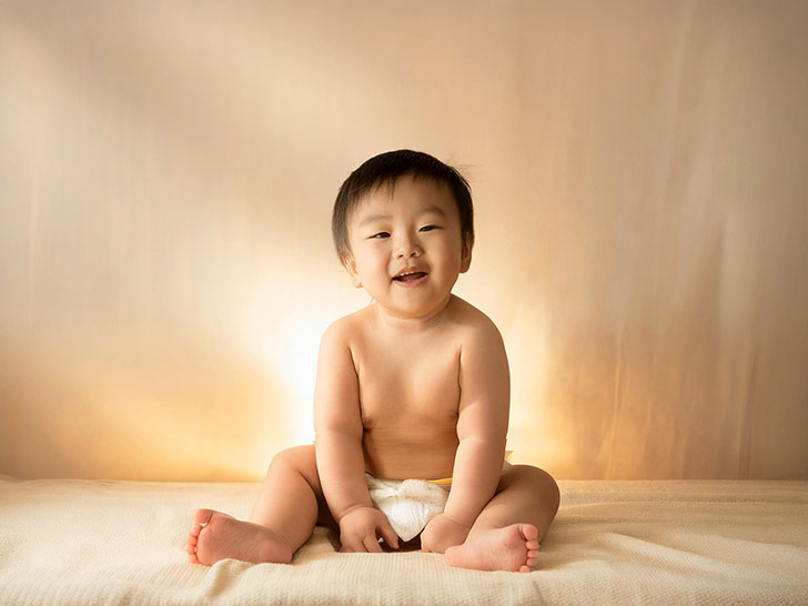 座ってとびきりの笑顔を見せる赤ちゃん
