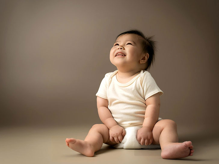 座ってとびきりの笑顔を見せる赤ちゃん
