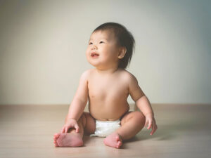 座ってとびきりの笑顔を見せる赤ちゃん