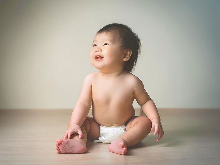 座ってとびきりの笑顔を見せる赤ちゃん
