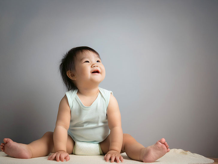座ってとびきりの笑顔を見せる赤ちゃん