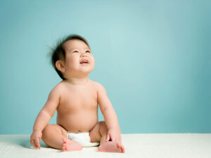座ってとびきりの笑顔を見せる赤ちゃん