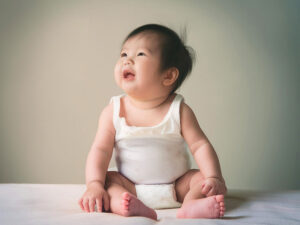 座ってとびきりの笑顔を見せる赤ちゃん