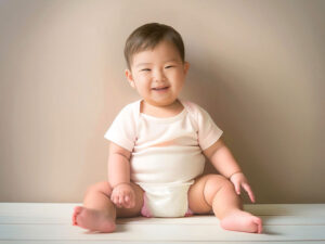 座ってとびきりの笑顔を見せる赤ちゃん