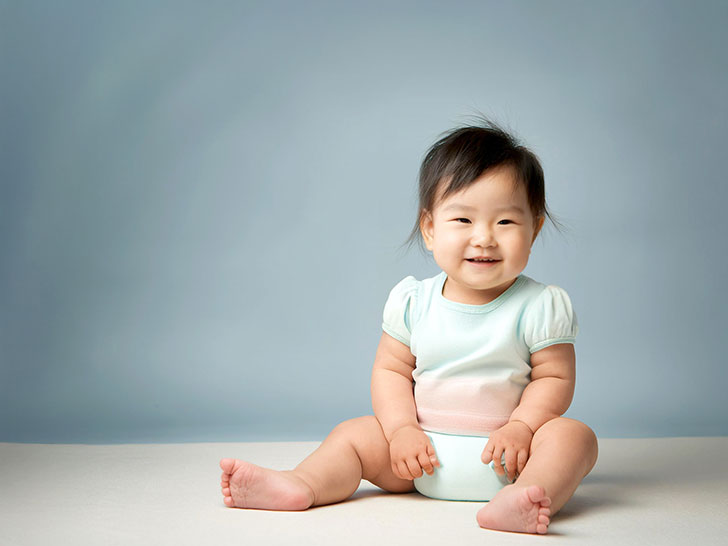 座ってとびきりの笑顔を見せる赤ちゃん