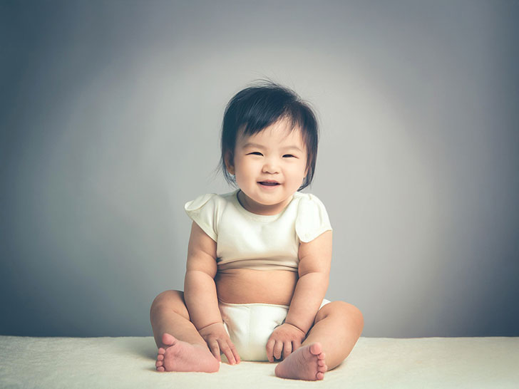 座ってとびきりの笑顔を見せる赤ちゃん