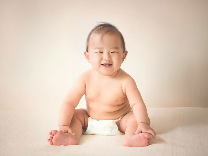 座ってとびきりの笑顔を見せる赤ちゃん