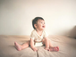 座ってとびきりの笑顔を見せる赤ちゃん