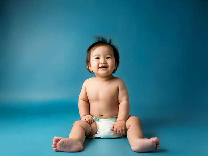 座ってとびきりの笑顔を見せる赤ちゃん