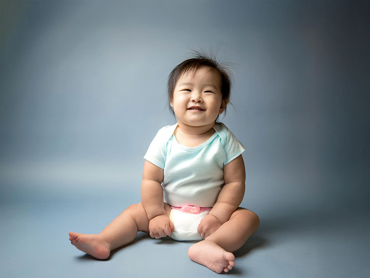 座ってとびきりの笑顔を見せる赤ちゃん