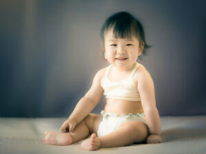 座ってとびきりの笑顔を見せる赤ちゃん